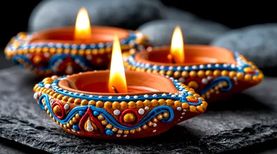 Three Lit Decorative Clay Diyas On Stone Surface