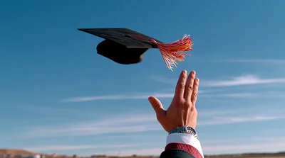 Graduate Throwing Academic Cap Into The Blue Sky