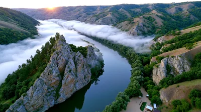 Aerial View Of A Winding River Through Foggy Mountains