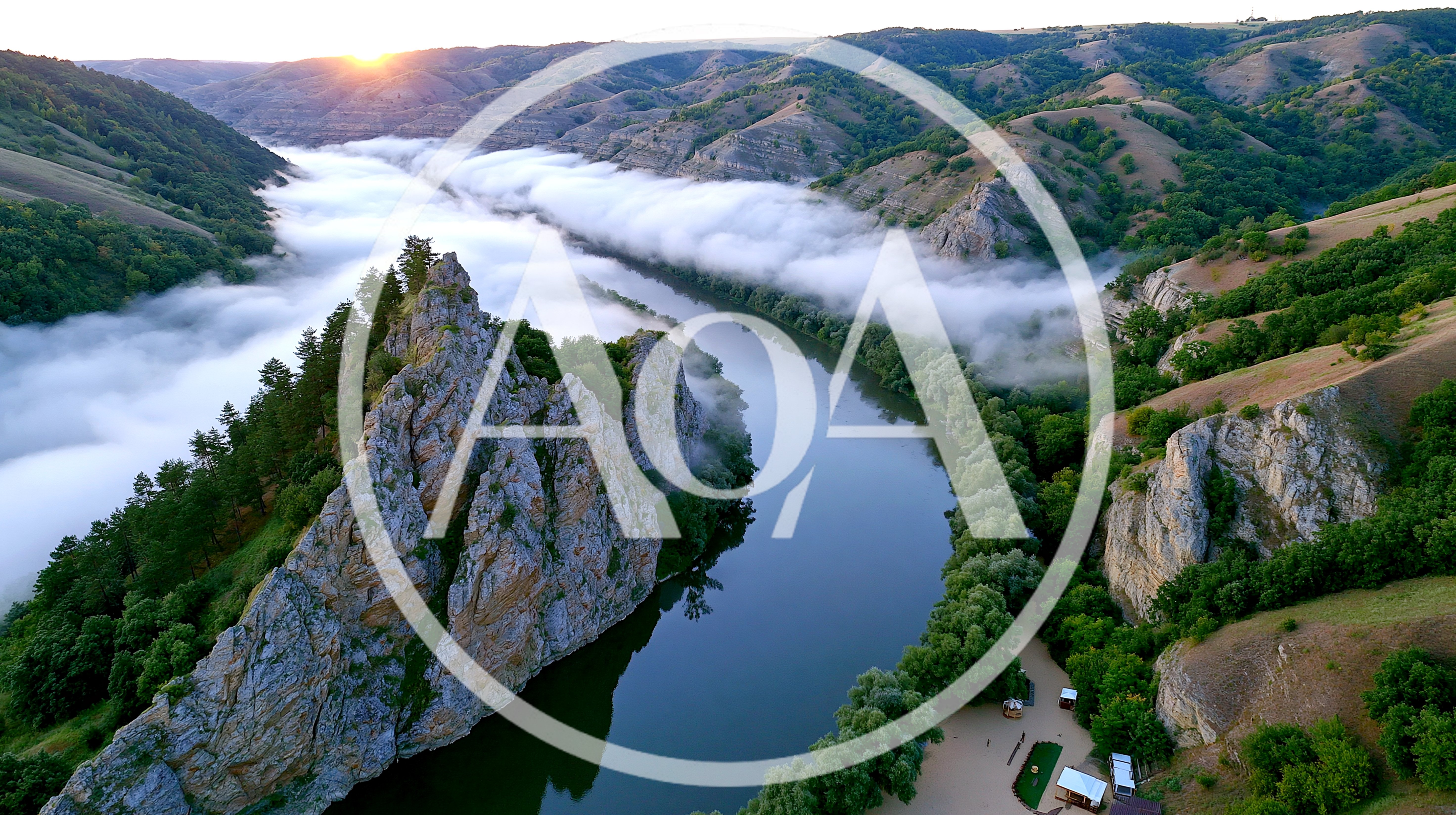 Aerial View Of A Winding River Through Foggy Mountains