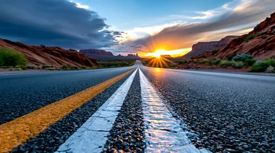 Empty Highway Leading Toward Monument Valley At Sunset