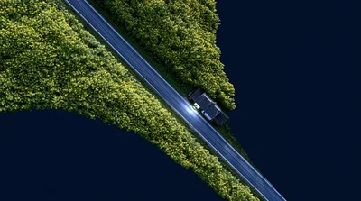 Aerial View Of A Car Driving On A Forest Road