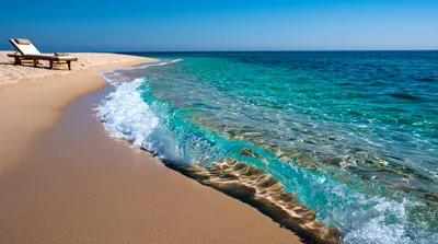 Empty Beach Lounge Chair By Turquoise Ocean Waves