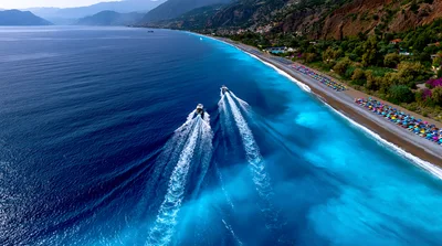 Two Speedboats Cruising Along A Vibrant Turquoise Coastline