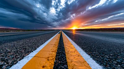 Empty Asphalt Road Leading Toward A Dramatic Sunset