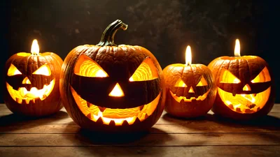 Four Glowing Jack O Lanterns On Wooden Table