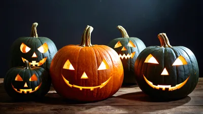 Five Glowing Jack O Lanterns On Wooden Table
