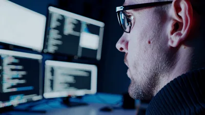 Software Developer Coding On Multiple Computer Monitors