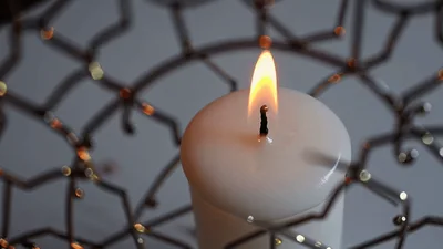 White Candle Burning Inside Decorative Metal Wire Bowl