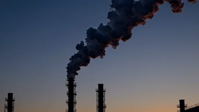Industrial Chimneys Emitting Thick Smoke Against Sunset Sky