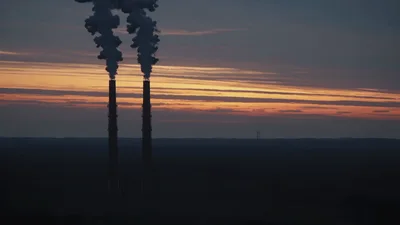 Industrial Chimneys Emitting Smoke Against Sunset Sky
