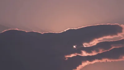 Bright Sun Emerging From Behind Dark Clouds At Sunset