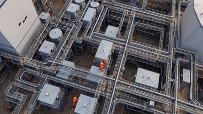 Industrial Workers Inspecting Complex Piping Infrastructure At Facility