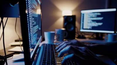 Software Developer Typing Code on Multiple Computer Monitors