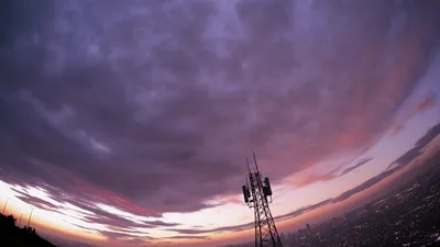 Cell Tower Silhouetted Against A Dramatic Purple Sunset
