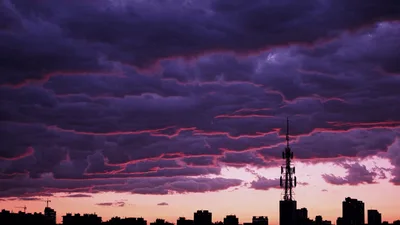 Dramatic Purple Sunset Clouds Over City Skyline Silhouette