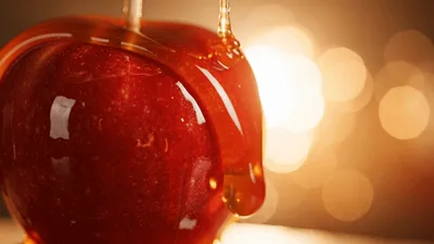 Golden Caramel Syrup Pouring Over A Shiny Red Apple