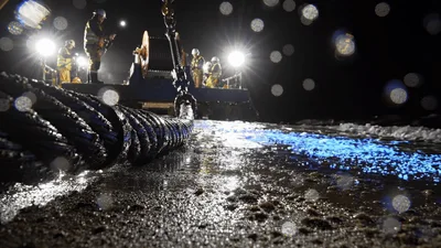 Workers Pulling Heavy Submarine Cable From Ocean At Night