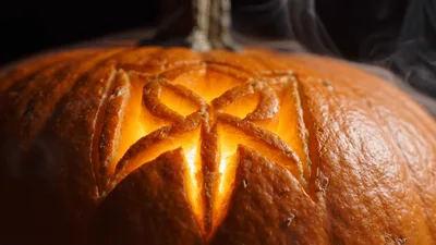 Carved Pumpkin With Glowing Light And Rising Smoke