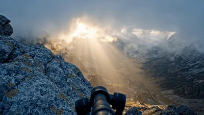 Sunlight Breaking Through Clouds Over Mountain Valley