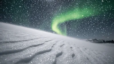 Aurora Borealis Shimmering Over Snowy Landscape At Night