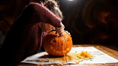 Young Woman Carving A Jack O Lantern Pumpkin