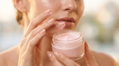 Woman Applying Pink Face Cream From Glass Jar