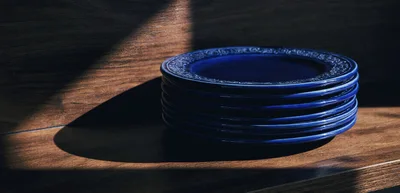 Stack of Blue Ceramic Plates on Wooden Shelf