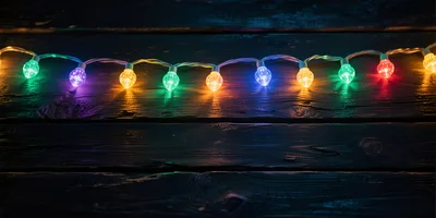 Colorful Christmas String Lights On Dark Wooden Background