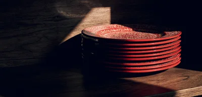 Stack of Red Ceramic Decorative Plates on Wooden Shelf