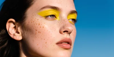 Portrait Of A Young Woman With Freckles And Yellow Eyeshadow