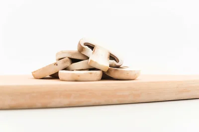 Sliced Raw Mushrooms On A Wooden Cutting Board