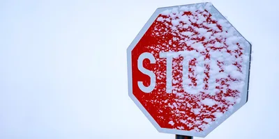 Snow Covered Stop Sign Against A White Sky