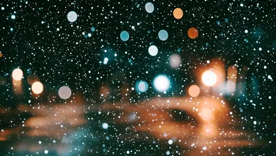 Snow Falling Against Blurred City Night Lights