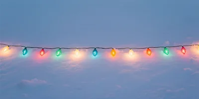 String Of Colorful Christmas Lights On Snowy Ground