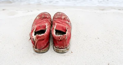 Worn Red Canvas Shoes On White Sandy Beach