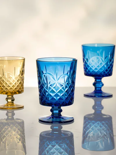 Three Elegant Colored Crystal Goblets On Reflective Surface