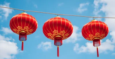 Three Traditional Red Chinese Lanterns Hanging Against Blue Sky