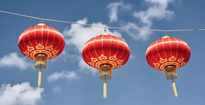 Three Traditional Red Chinese Lanterns Hanging Against Blue Sky