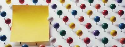 Yellow Sticky Note Surrounded By Colorful Push Pins