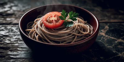 Steaming Bowl Of Whole Wheat Spaghetti With Tomato Garnish