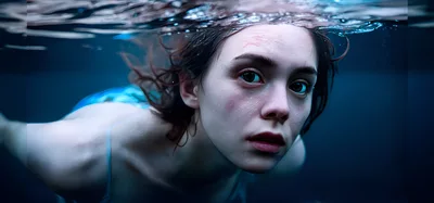 Young Woman Swimming Underwater In A Dark Pool
