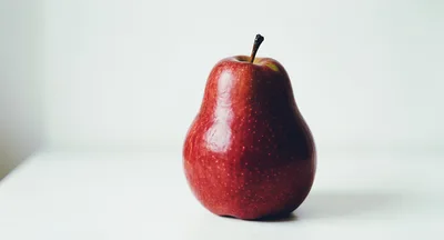 A Single Red Pear On A White Surface