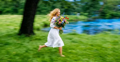 Young Woman Running Through Park With Flower Bouquet