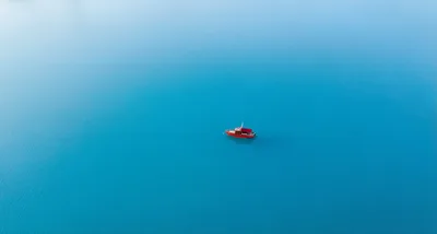 Small Red Boat Floating on Calm Blue Water