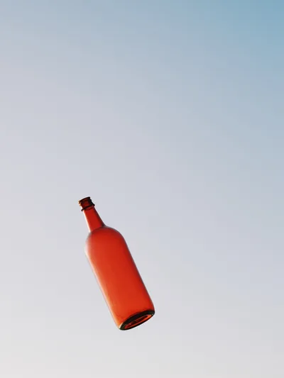 Red Glass Bottle Floating Against Clear Blue Sky