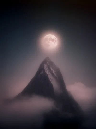 Full Moon Rising Above A Misty Mountain Peak