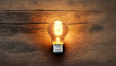 Glowing Spiral Filament Light Bulb On Wooden Surface