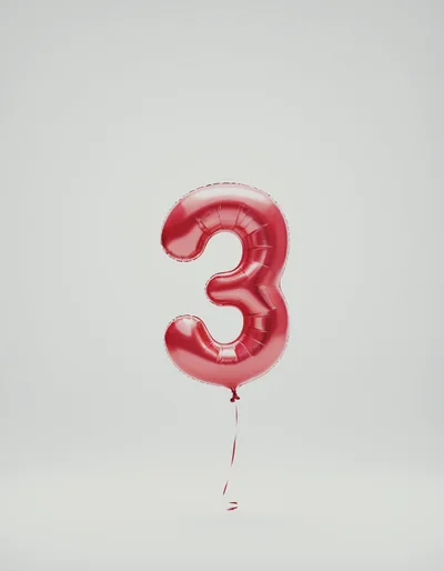 Red Number Three Balloon Floating Against A Neutral Background