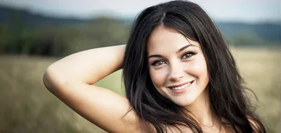 Smiling Young Woman Posing In A Grassy Field